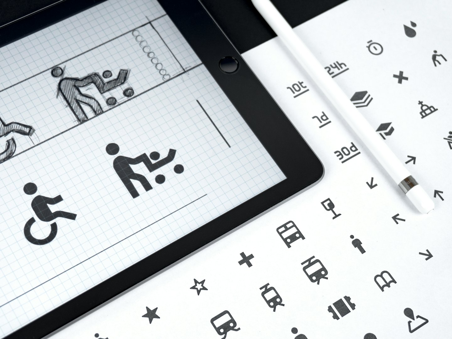 Tablet con concetti di graphic design accanto a uno stilo e un foglio di icone.